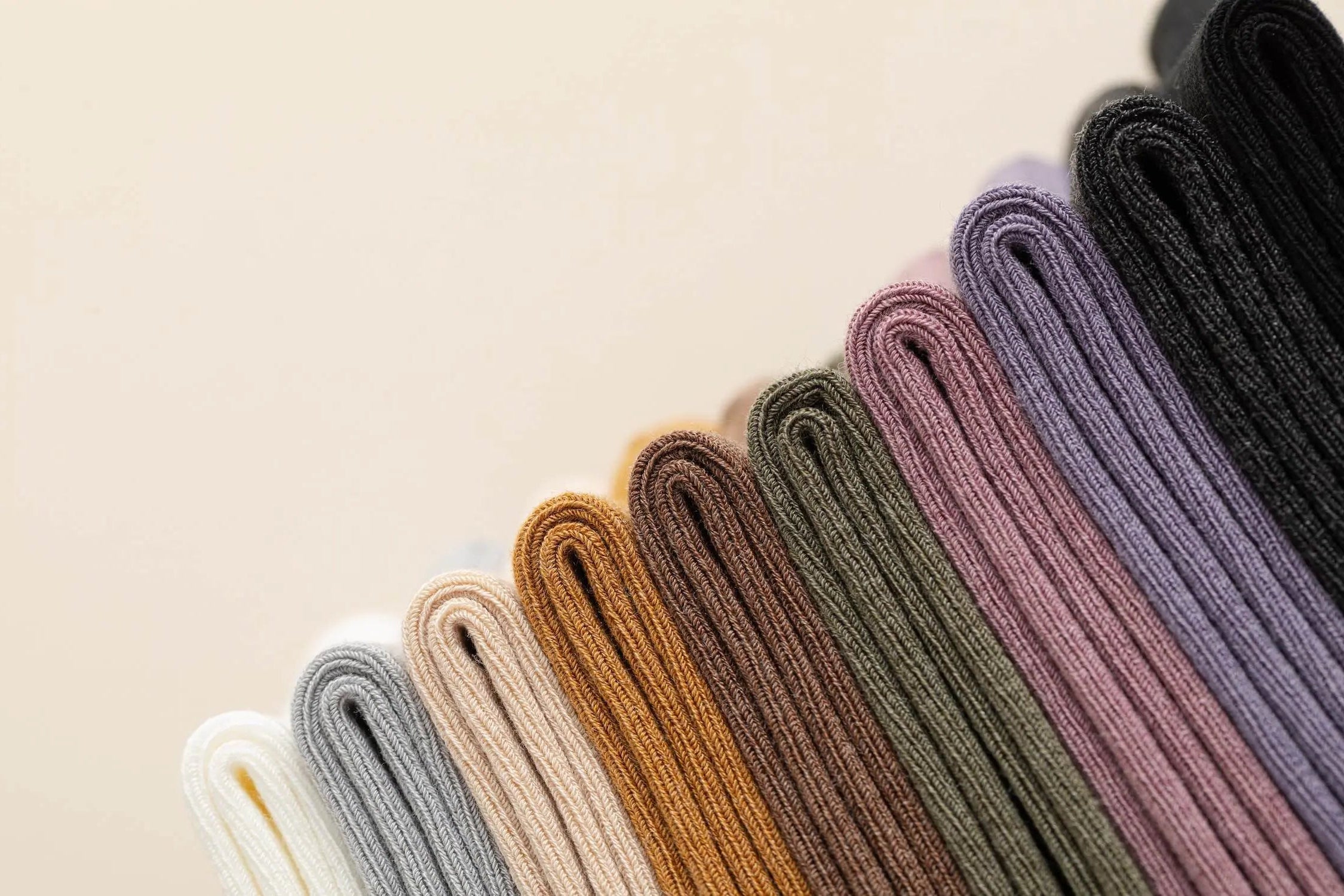 Row of folded socks in various colors on a neutral background
