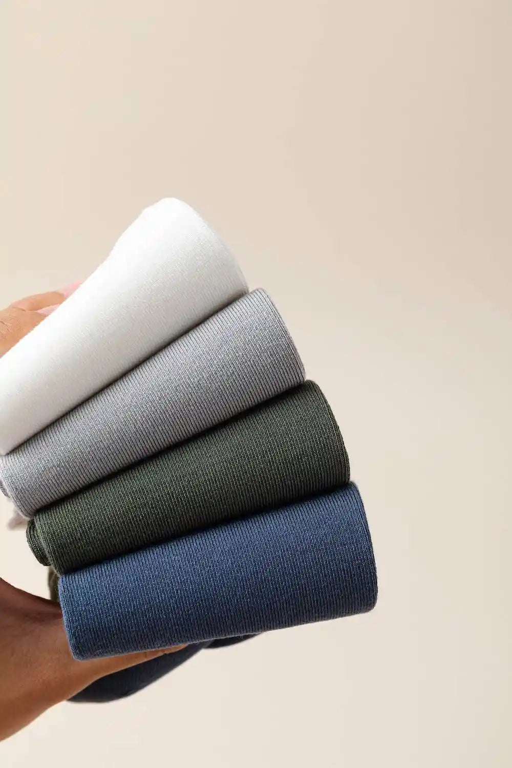 Row of folded socks in various colors on a neutral background